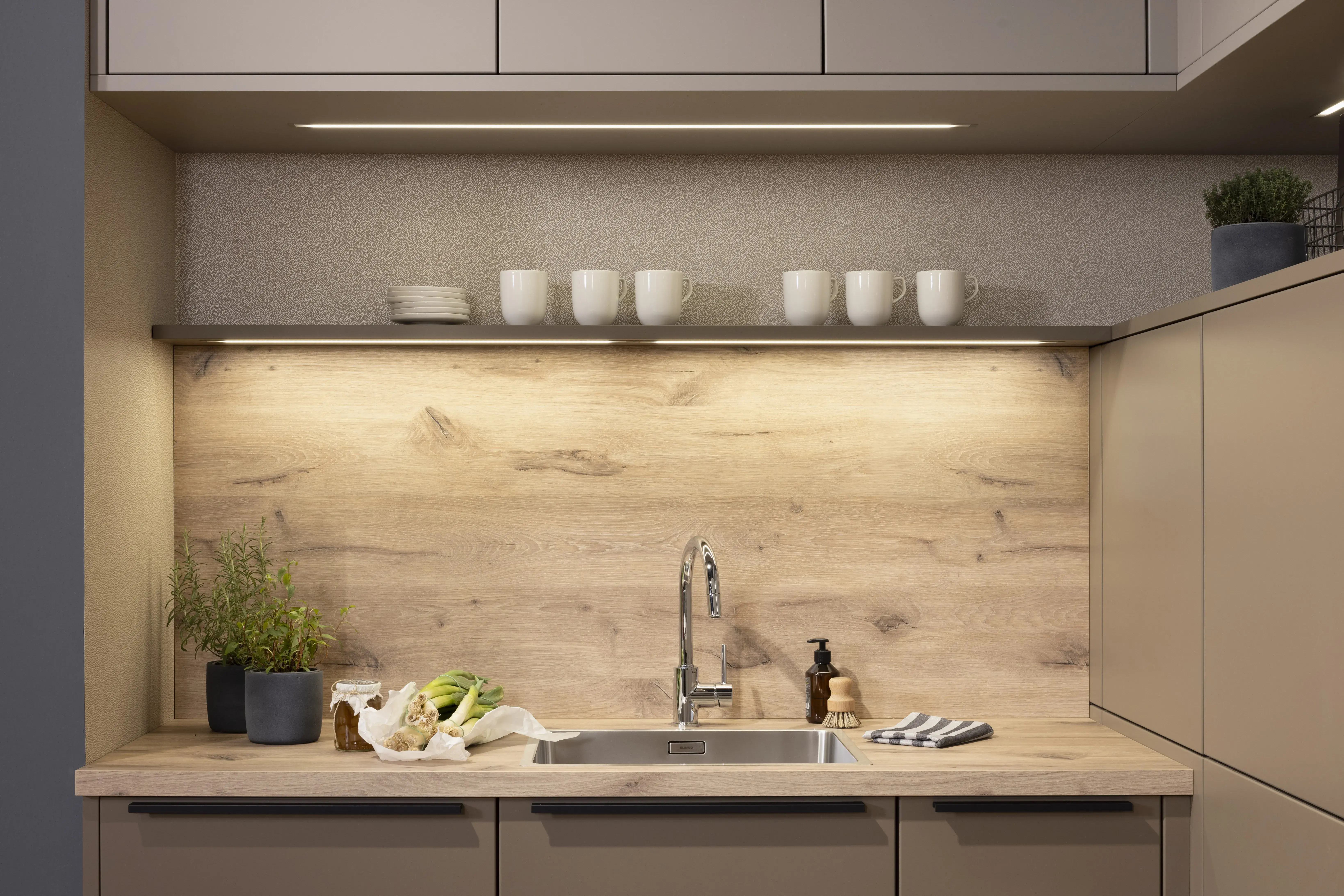 APL: Patagonia Eiche NB Front: Kaschmirbraun satin Front: Sepiabraun satin Korpus: Lavaschwarz Griff: Metall Schwarz Geräte: Bosch Armatur: Blanco Spüle: Blanco   Features: Farbkombination mit zwei Brauntönen kombiniert mit Eiche APL und Nischenrückwand (NB), Oberschrankplanung, Ablageraum auf Augenhöhe, Thekenlösung mit Tisch, Dunstabzugshaube (Airforce), Edelstahl Aufsatzspüle, Schiebeelemente.