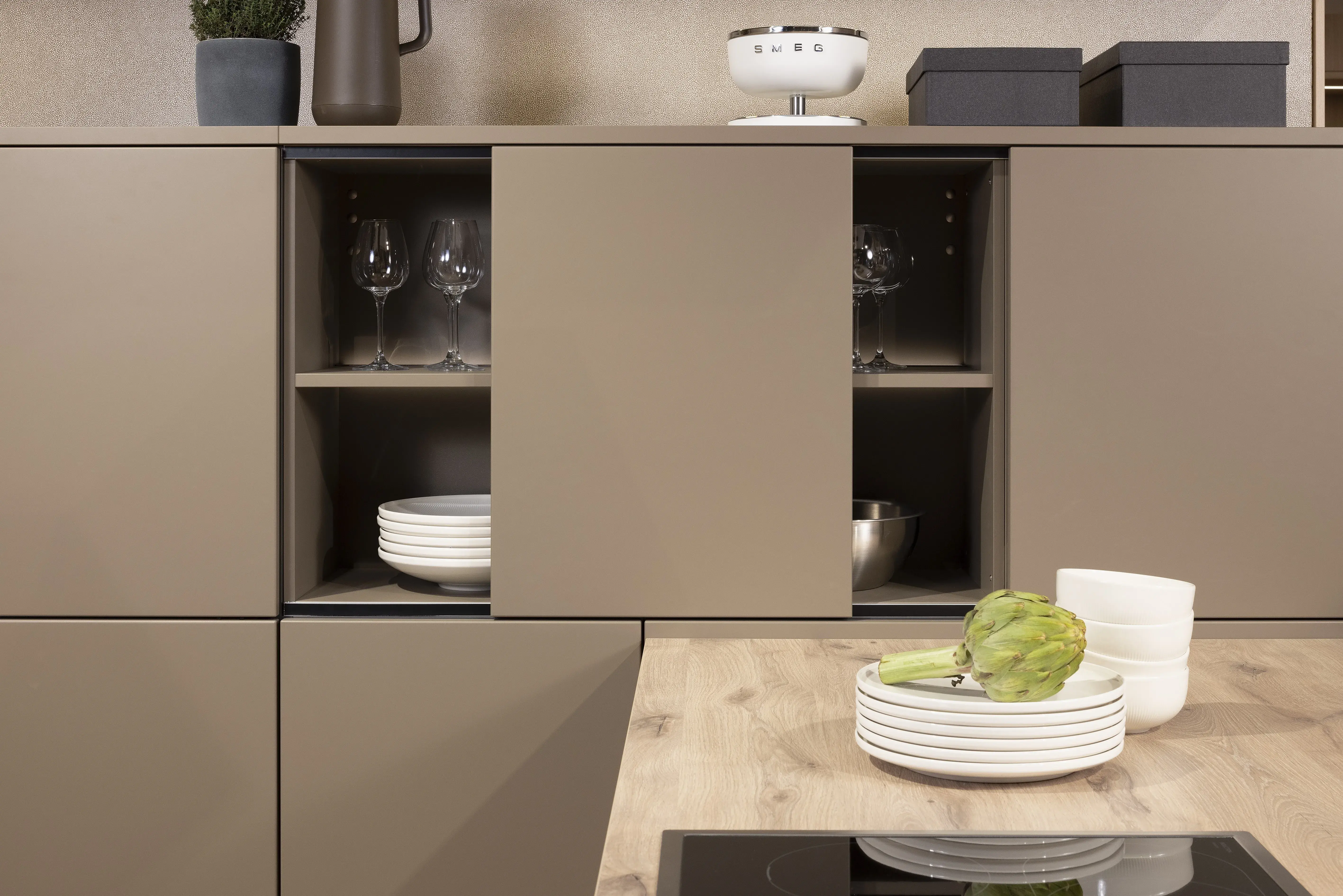 APL: Patagonia Eiche NB Front: Kaschmirbraun satin Front: Sepiabraun satin Korpus: Lavaschwarz Griff: Metall Schwarz Geräte: Bosch Armatur: Blanco Spüle: Blanco   Features: Farbkombination mit zwei Brauntönen kombiniert mit Eiche APL und Nischenrückwand (NB), Oberschrankplanung, Ablageraum auf Augenhöhe, Thekenlösung mit Tisch, Dunstabzugshaube (Airforce), Edelstahl Aufsatzspüle, Schiebeelemente.