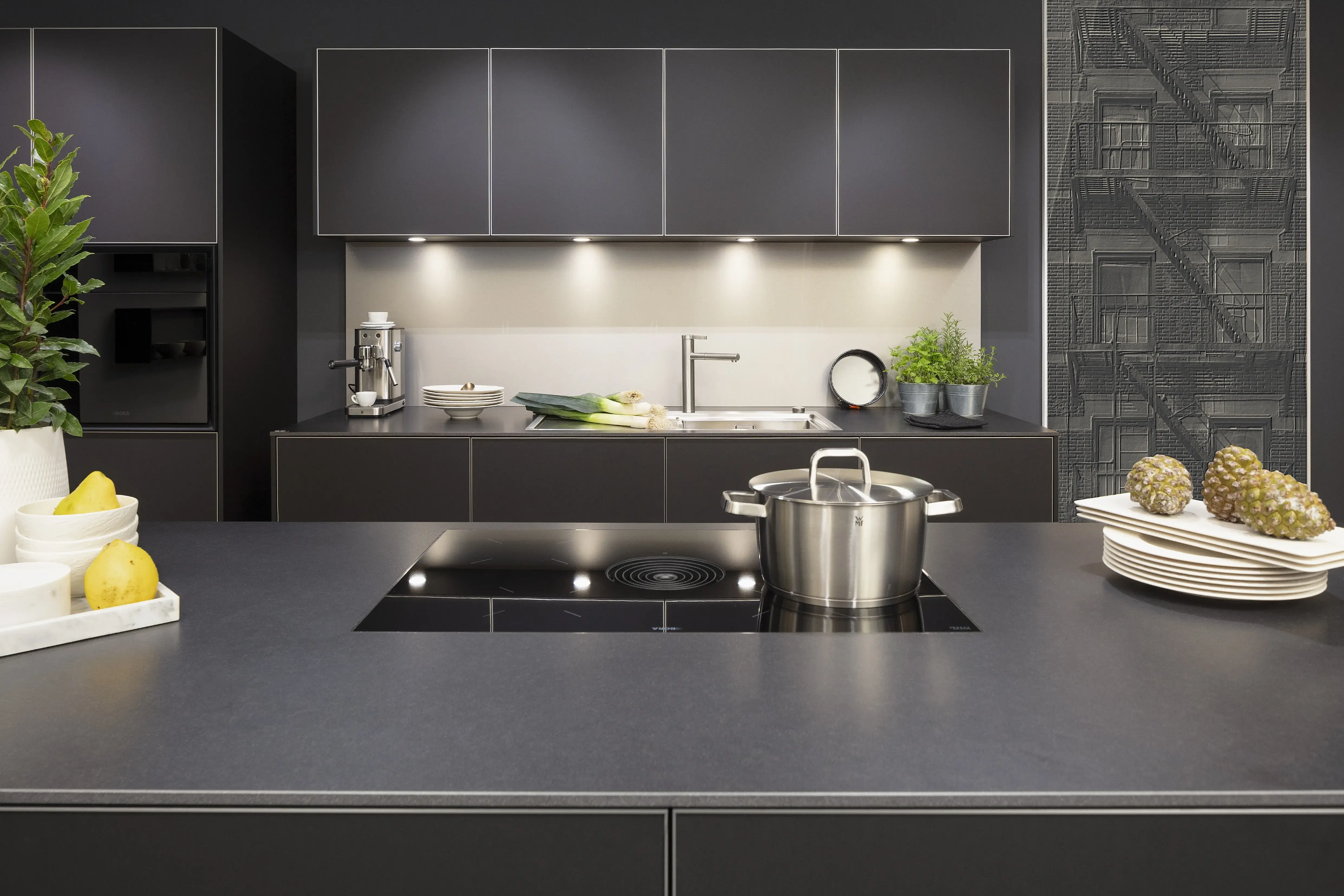 Front: Alu Tec RP Resopal Schwarz supermatt, Aluminiumkante APL: Schwarz Mikrostruktur  Geräte: Bora  Armatur und Spüle: Blanco  Features: stringentes Raster, Oberschränke quadratisch, Aluminiumkante, Regalsystem mit LED, Korpus Resopal Schwarz, Downlights, Schwarz/Edelstahl, Regale mit Edelstahlrückwand, Schubladen Holzfurnier. 