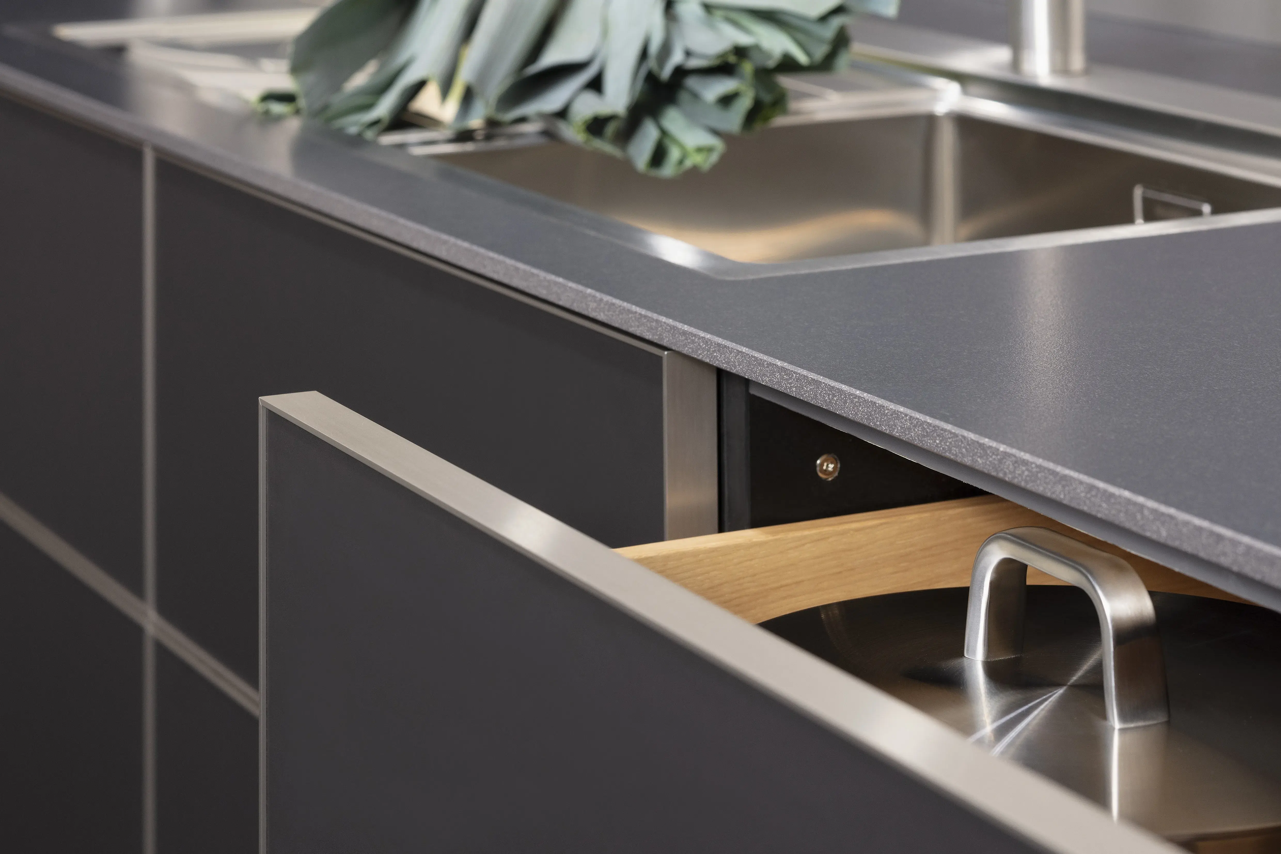 Front: Alu Tec RP Resopal Schwarz supermatt, Aluminiumkante APL: Schwarz Mikrostruktur  Geräte: Bora  Armatur und Spüle: Blanco  Features: stringentes Raster, Oberschränke quadratisch, Aluminiumkante, Regalsystem mit LED, Korpus Resopal Schwarz, Downlights, Schwarz/Edelstahl, Regale mit Edelstahlrückwand, Schubladen Holzfurnier. 